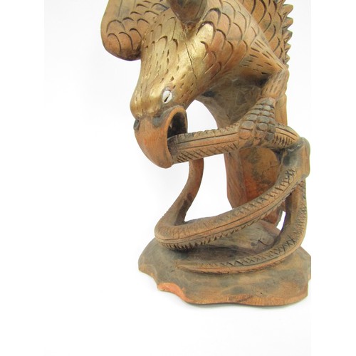 9051 - A handpainted carved wooden Eagle inset with shell eyes with a snake in its mouth, 54cm tall, 20cm w... 