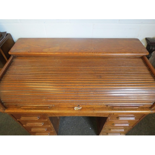 1040 - An early 20th Century oak rolltop desk with green leather insert (worn), eight drawers and two brush... 