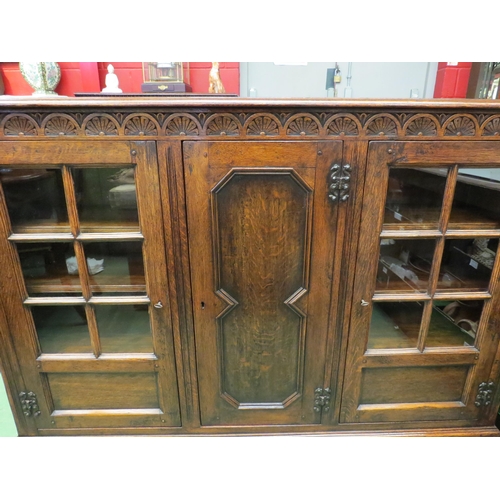 4057 - In the manner of Titchmarsh & Goodwin a carved oak three door bookcase (two panel glazed) with two k... 