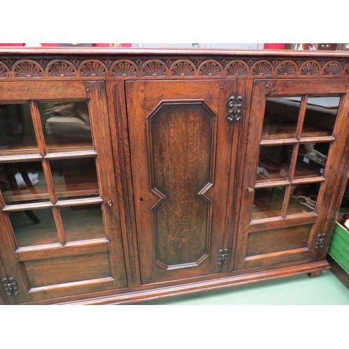 4057 - In the manner of Titchmarsh & Goodwin a carved oak three door bookcase (two panel glazed) with two k... 