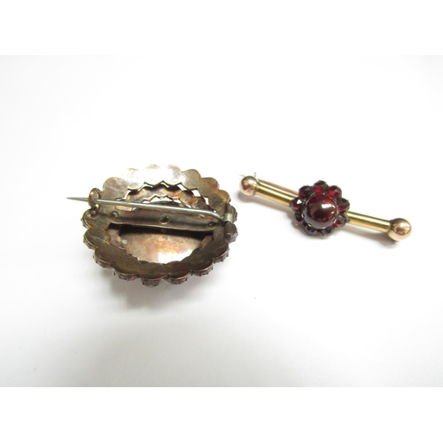 4381 - A garnet brooch the central cabochon roundel framed by stepped rows of garnets, 3cm diameter with a ... 