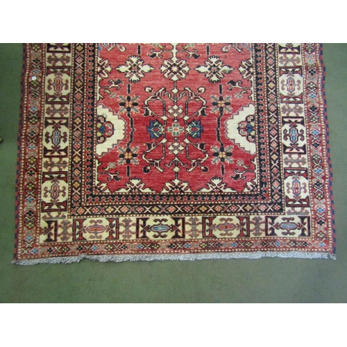 4023 - A red ground wool rug with multiple borders, 182cm x 113cm