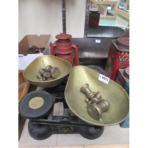 9073 - Two iron sets of scales with brass weights and a storm lamp