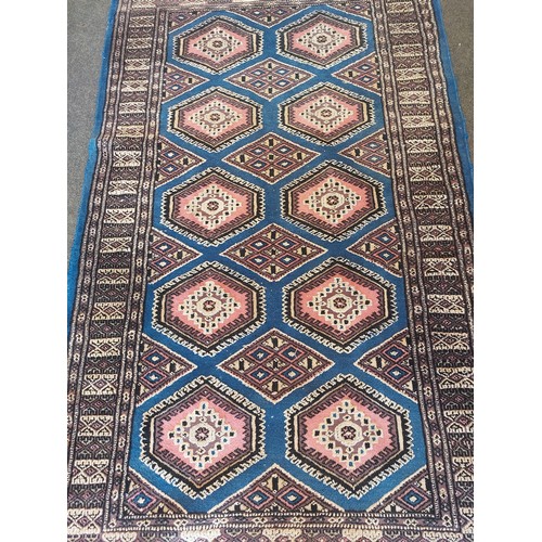 1019 - A blue and pink ground wool and cotton rug with diamond lozenges and geometric border, 165cm x 95cm