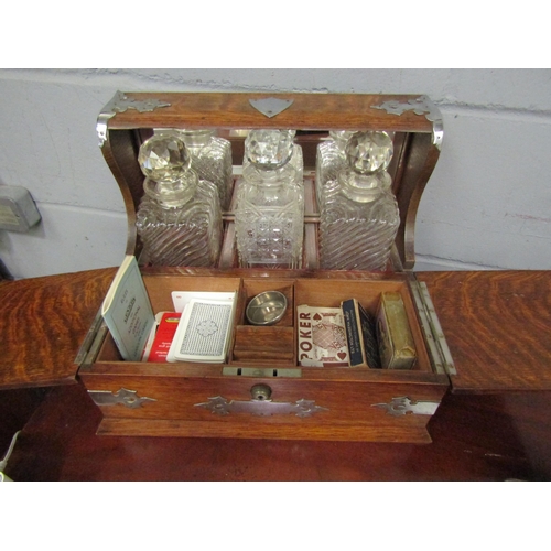 1044 - An Edwardian oak tantalus/games compendium with three decanters, one associated