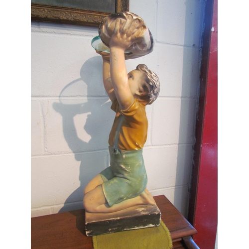 1003 - A chalkware display stand in the form of a boy holding a glass plate aloft, 61cm tall