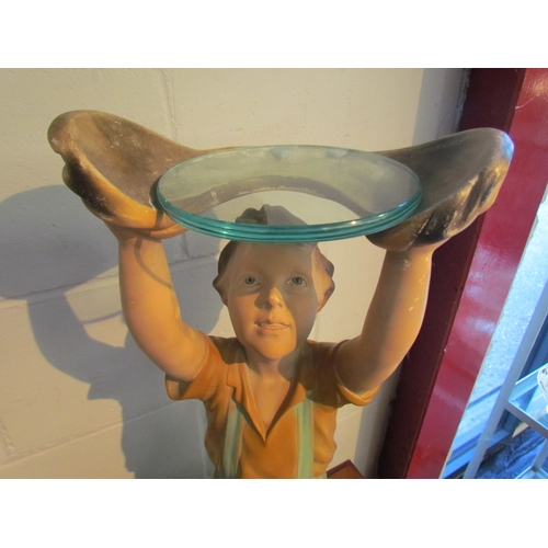 1003 - A chalkware display stand in the form of a boy holding a glass plate aloft, 61cm tall