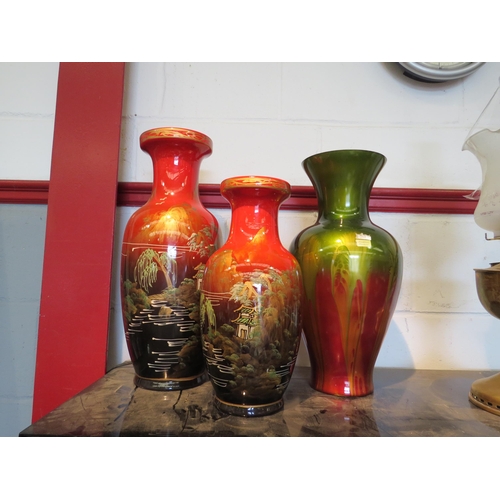 1537 - A graduated pair of Oriental vases overpainted in red and a similar glass example (3)