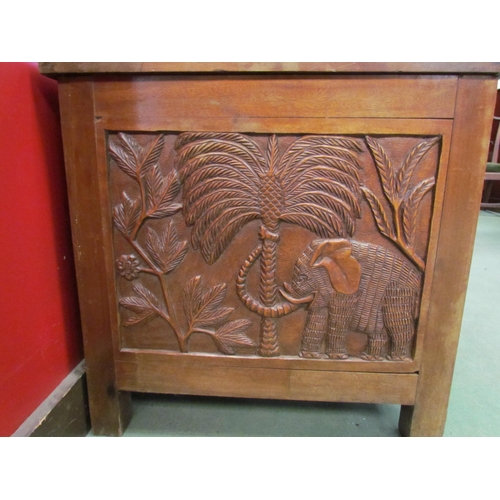 4016 - A heavily carved African blanket chest depicting figures and animals under palms, 56cm tall x 94cm w... 