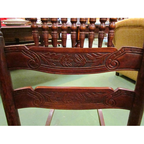 4190 - An Arts & Crafts carved oak rocking chair with ring turned spindle supports having bentwood arms ove... 