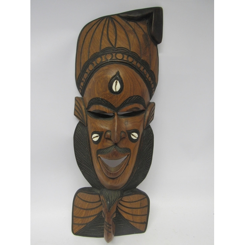 1188 - A carved hardwood tribal style wall mask inset with three cowrie shells, 55cm tall