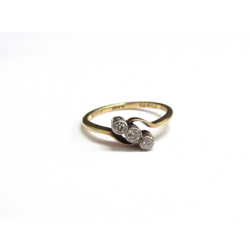 8065 - A gold three stone diamond crossover ring. Size M, 2g