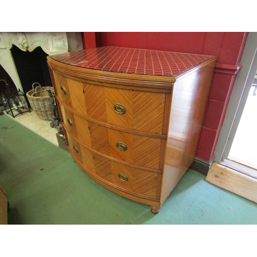 4154 - A satin walnut bow-front chest of three long drawers with decorative brass oval handles on tapering ... 