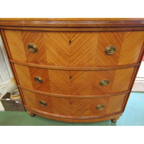 4154 - A satin walnut bow-front chest of three long drawers with decorative brass oval handles on tapering ... 