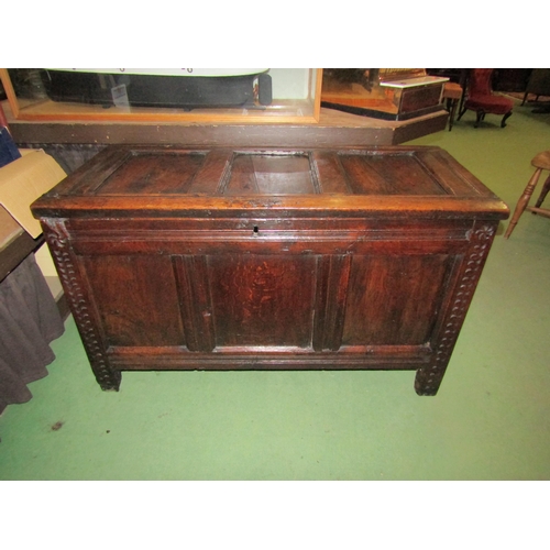 4005 - An 18th Century pegged oak three panel coffer the hinged lid over carved end stile feet, 70cm x 115c... 