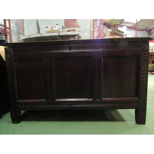 4005 - An 18th Century pegged oak three panel coffer the hinged lid over carved end stile feet, 70cm x 115c... 