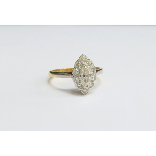 8021 - An 18ct gold platinum set diamond ring, the central marquise cut diamond framed by ten round cut dia... 