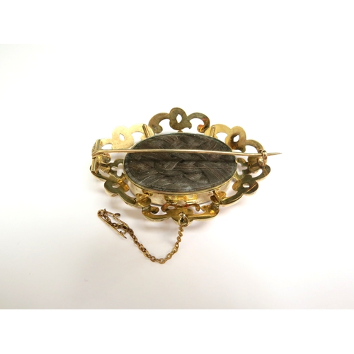 8043 - A Victorian memoriam brooch the centre oval glass panel with ornate flower and frond hair detail, in... 