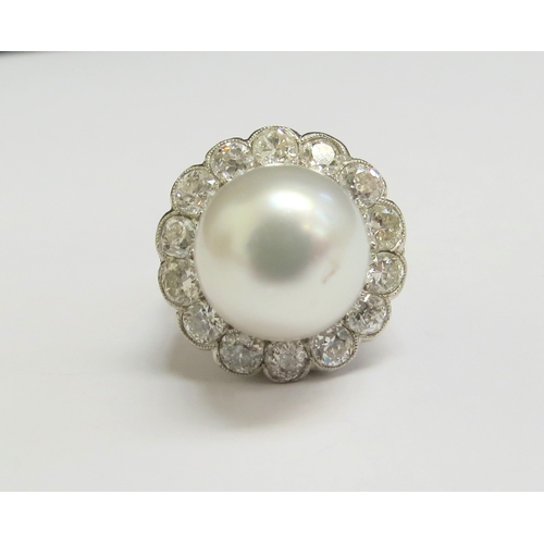 8008 - A platinum ring set with a large pearl 12mm diameter framed by fourteen diamonds, 1.40ct total appro... 