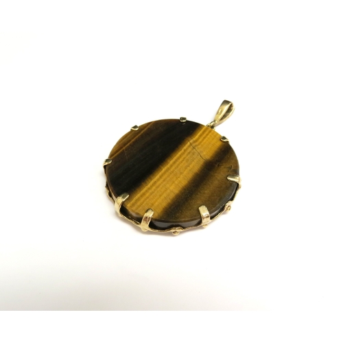 8005 - A tiger's eye circular pendant framed in a 9ct gold mount with gold Archer (Sagittarius) to centre, ... 