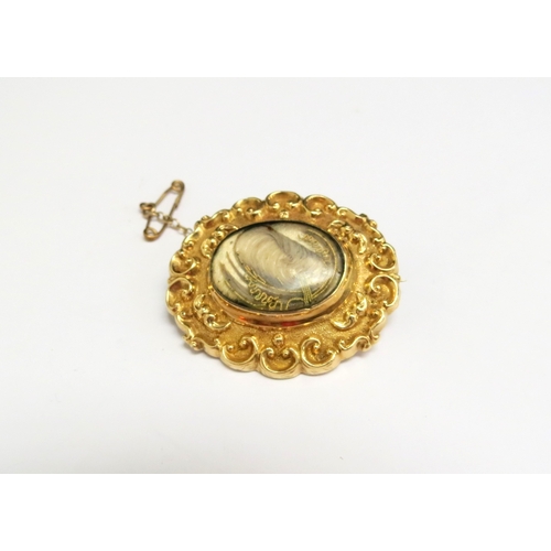 8069 - A 19th Century memoriam brooch with central hair panel in a scroll frame, reverse inscribed 