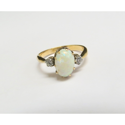 8056 - An 18ct gold opal and diamond ring, the oval cabochon opal flanked by diamonds. Size L/M, 2.3g