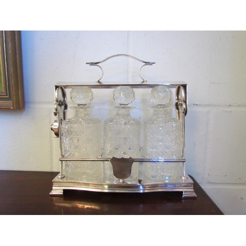 1014 - A silver plated tantalus with three decanters, one chipped