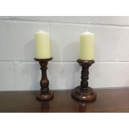 1037 - Two turned wooden candle stands with large candles, stands approximately 22cm tall