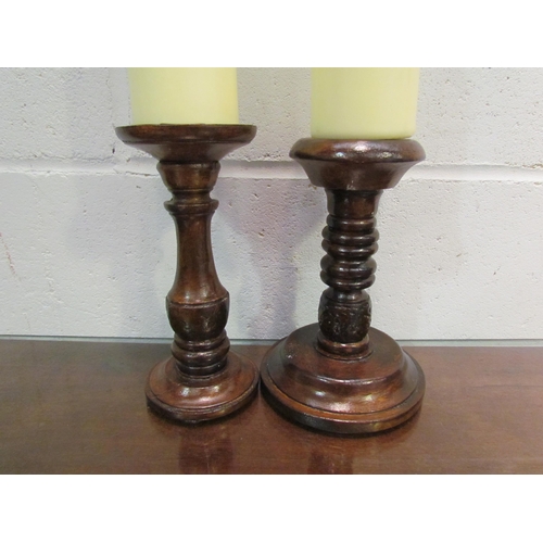 1037 - Two turned wooden candle stands with large candles, stands approximately 22cm tall