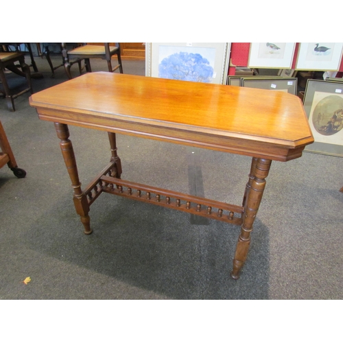 1123 - An Edwardian walnut table, canted corners, ring-turned legs joined by a spindle stretcher, 68cm tall... 