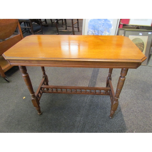 1123 - An Edwardian walnut table, canted corners, ring-turned legs joined by a spindle stretcher, 68cm tall... 