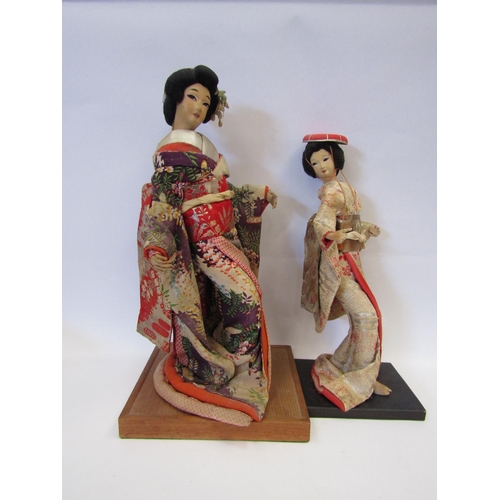 1002 - A ceramic Japanese female figure in traditional fabric clothing, cased, together with two other simi... 