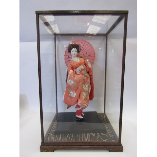 1002 - A ceramic Japanese female figure in traditional fabric clothing, cased, together with two other simi... 