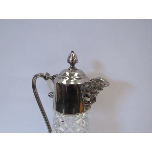 1319 - A glass claret jug with silver plated top and face form spout, 28cm tall