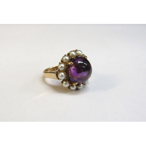 8294 - A gold amethyst and pearl ring, the central cabochon amethyst framed by pearls, 17mm diameter stampe... 