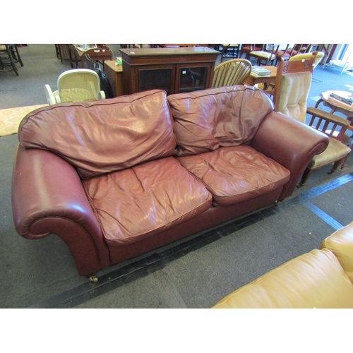 1154 - A Laura Ashley large two seater leather sofa with scrolled arms on castors