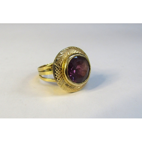 8308 - A gold ring set with a circular amethyst in a wide etched frame. Size L/M, 5g