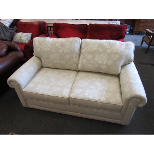 1153 - A John Lewis cream upholstered two seater sofa with foliate design, converts to bed