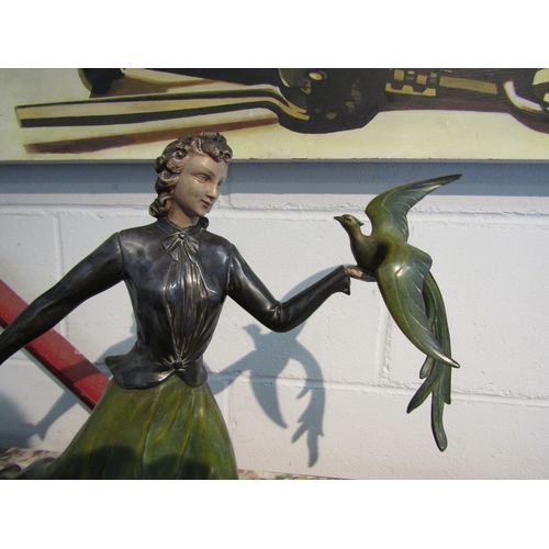 1002 - A painted bronze figure of a lady holding bird on marble base, 33cm tall x 51cm long   (R) £75