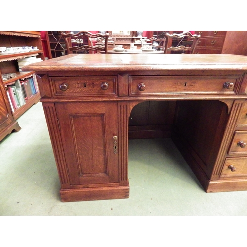 4116 - A circa 1900 panelled oak twin pedestal desk, the gilt tooled leather insert over six drawers and si... 