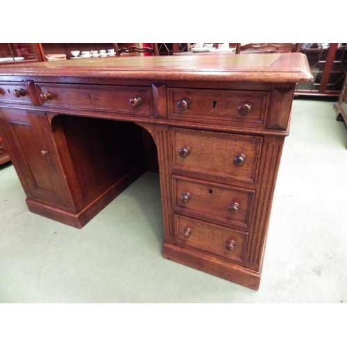 4116 - A circa 1900 panelled oak twin pedestal desk, the gilt tooled leather insert over six drawers and si... 