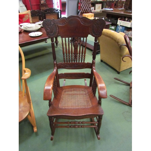 4226 - An Arts & Crafts carved oak rocking chair with ring turned spindle supports having bentwood arms ove... 