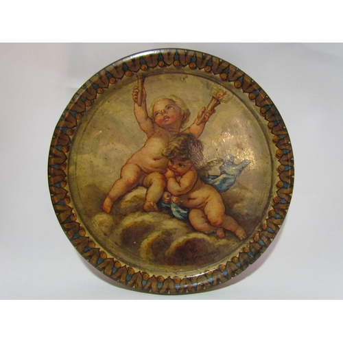 4257 - A pottery charger depicting putti, one holding two torches, hand-painted and indistinctly signed at ... 