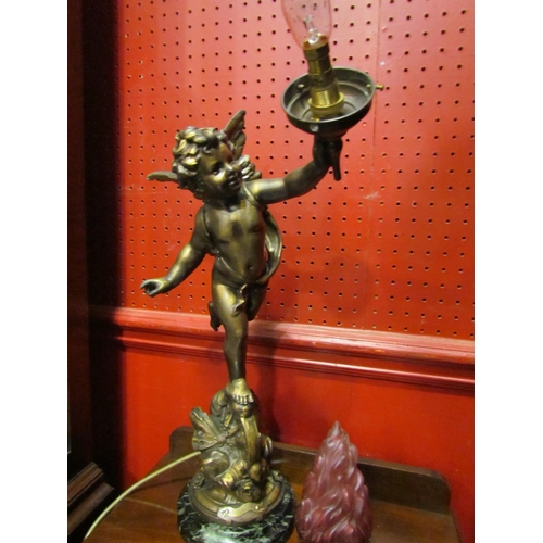 4036 - A gilt metal table lamp base in the form of a winged cherub holding flame shade aloft, bearing plaqu... 