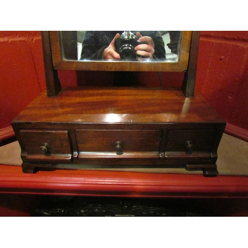 4137 - A 19th Century mahogany toilet mirror, the tilting mirror and brass finials over a three drawer base... 