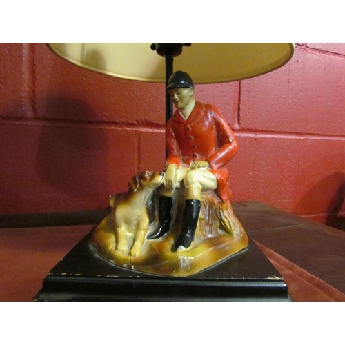 4141 - A vintage plaster table lamp, seated huntsman with his hound, wooden plinth form base