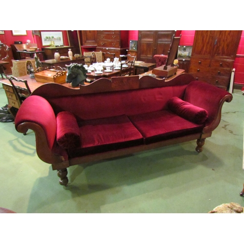 4164 - A Victorian scroll end sofa on turned legs with castors with red velour upholstery and bolster cushi... 