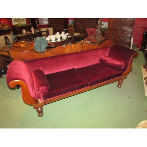 4164 - A Victorian scroll end sofa on turned legs with castors with red velour upholstery and bolster cushi... 