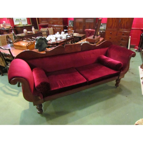 4164 - A Victorian scroll end sofa on turned legs with castors with red velour upholstery and bolster cushi... 