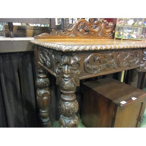 4202 - A carved oak 'Green Man' style side table, 91cm tall x 113cm wide x 43cm deep